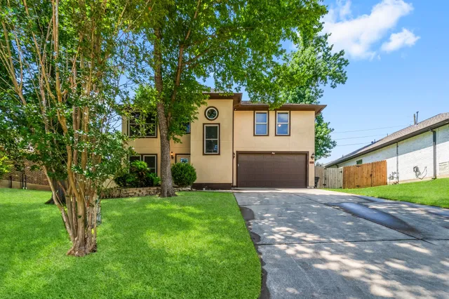 a front view of a house with a yard and a tree