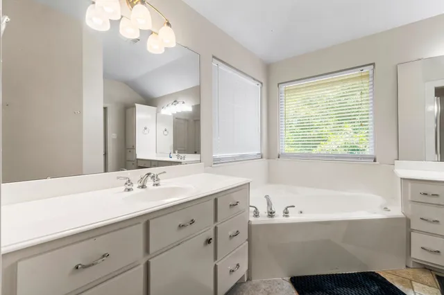a bathroom with a tub sink and mirror