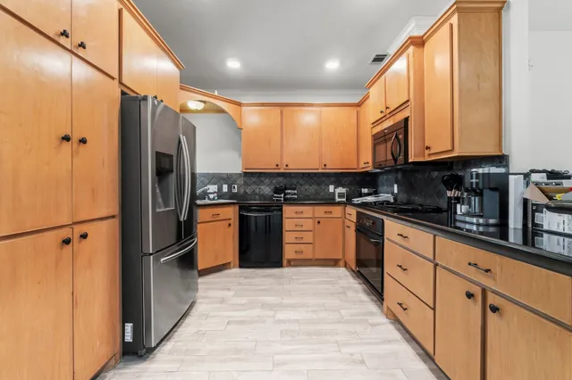 a kitchen with granite countertop a stove sink cabinets and refrigerator