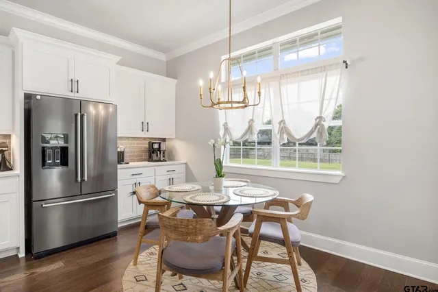 a kitchen with stainless steel appliances a refrigerator a stove a dining table and chairs