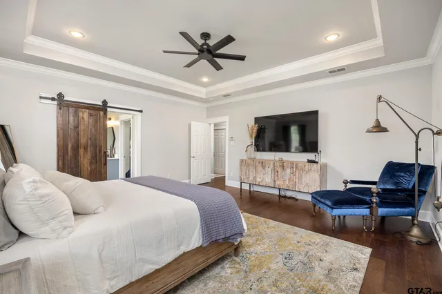 a spacious bedroom with a bed a flat screen tv and a couch