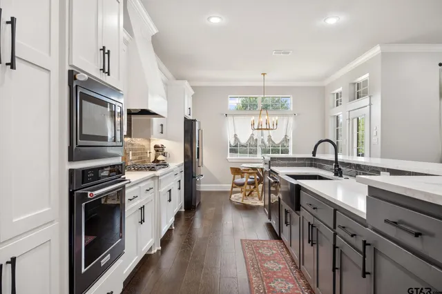 a kitchen with stainless steel appliances granite countertop a sink stove oven a refrigerator with white cabinets and wooden floor