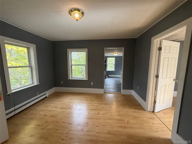 a view of an empty room with glass door and wooden floor