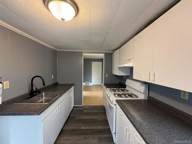 a kitchen with stainless steel appliances granite countertop a sink a stove and a wooden floors