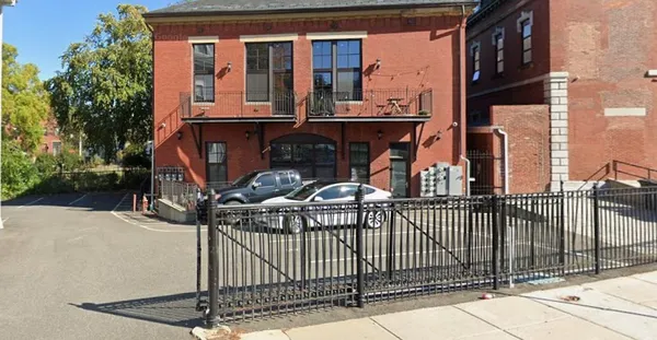 a view of a brick house with large windows and a small yard