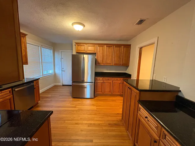 a kitchen with stainless steel appliances granite countertop a refrigerator a stove and a microwave with wooden floor