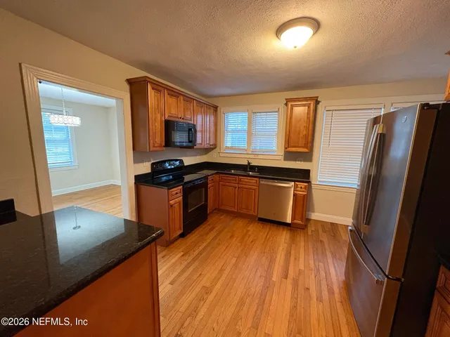 a kitchen with stainless steel appliances granite countertop a refrigerator a sink dishwasher a stove with wooden floor and cabinets