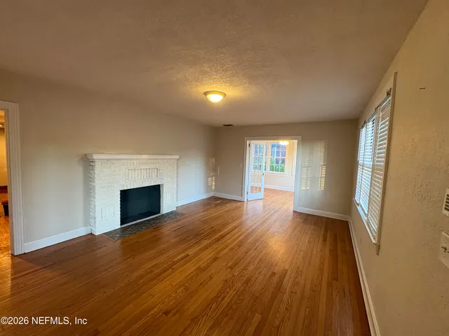 a view of empty room with wooden floor and fireplace