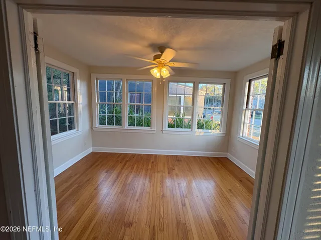 a view of an empty room with wooden floor and a window