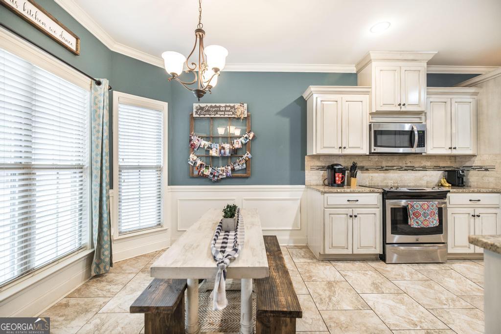 312 Bridgehampton Way Perry, GA 31069 - Photo 12 of 34 a kitchen with stainless steel appliances granite countertop a stove top oven a sink a dining table and chairs with wooden floor