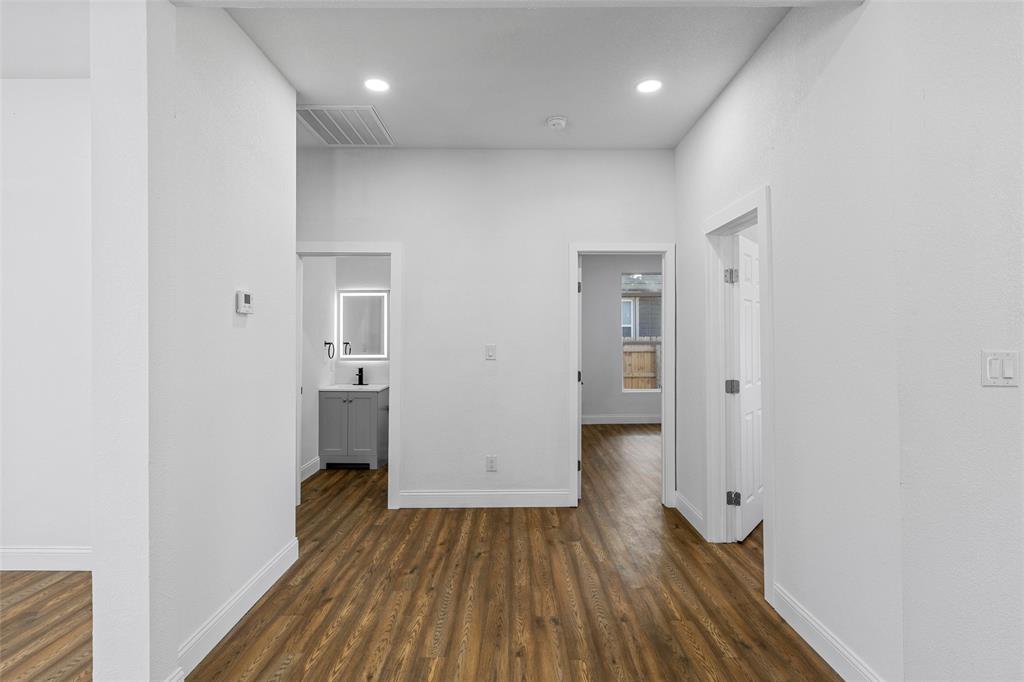 2023 Bosque Boulevard Waco, TX 76707 - Photo 12 of 26 Hallway featuring wood-finish flooring, white baseboards, and bright white walls