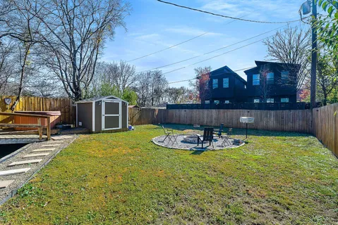 a view of a backyard with table and chairs a barbeque and wooden fence