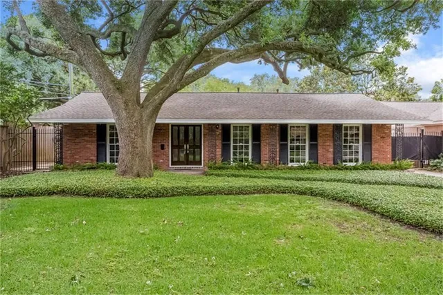 a brick house next to a yard with a large tree