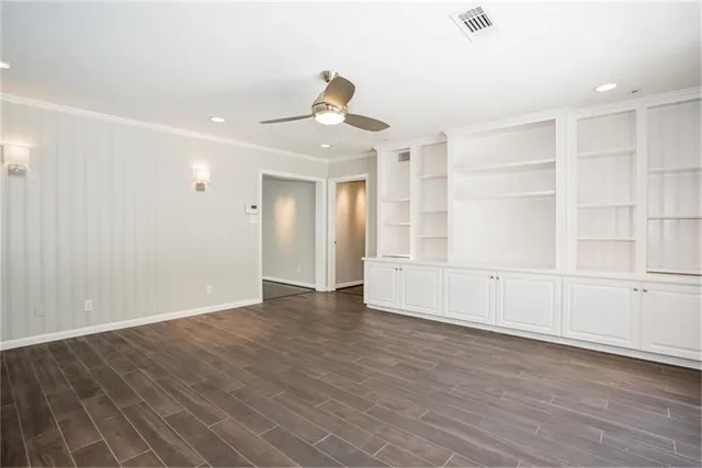 a view of an empty room with wooden floor and windows
