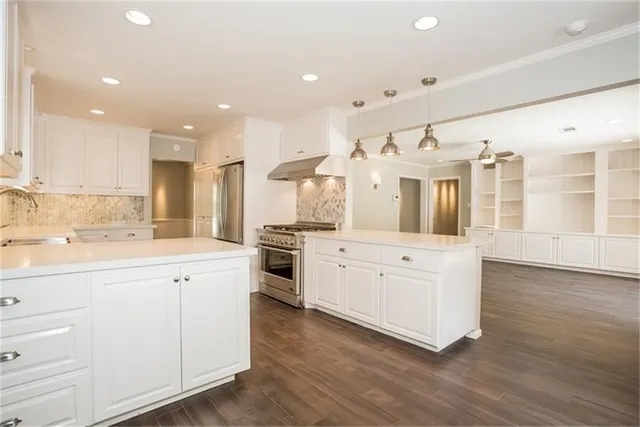 a kitchen with stainless steel appliances kitchen island hardwood floor sink and stove