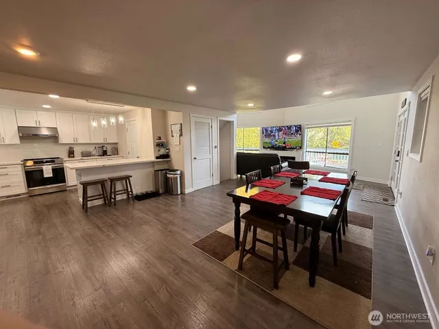 a living room with stainless steel appliances kitchen island granite countertop furniture wooden floor and a kitchen view