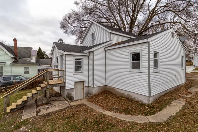 a view of a white house with a yard and stairs