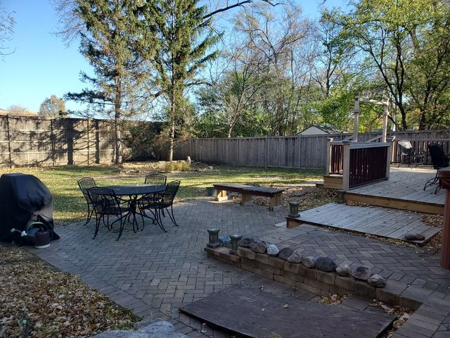 a view of a backyard with table and chairs potted plants and tree