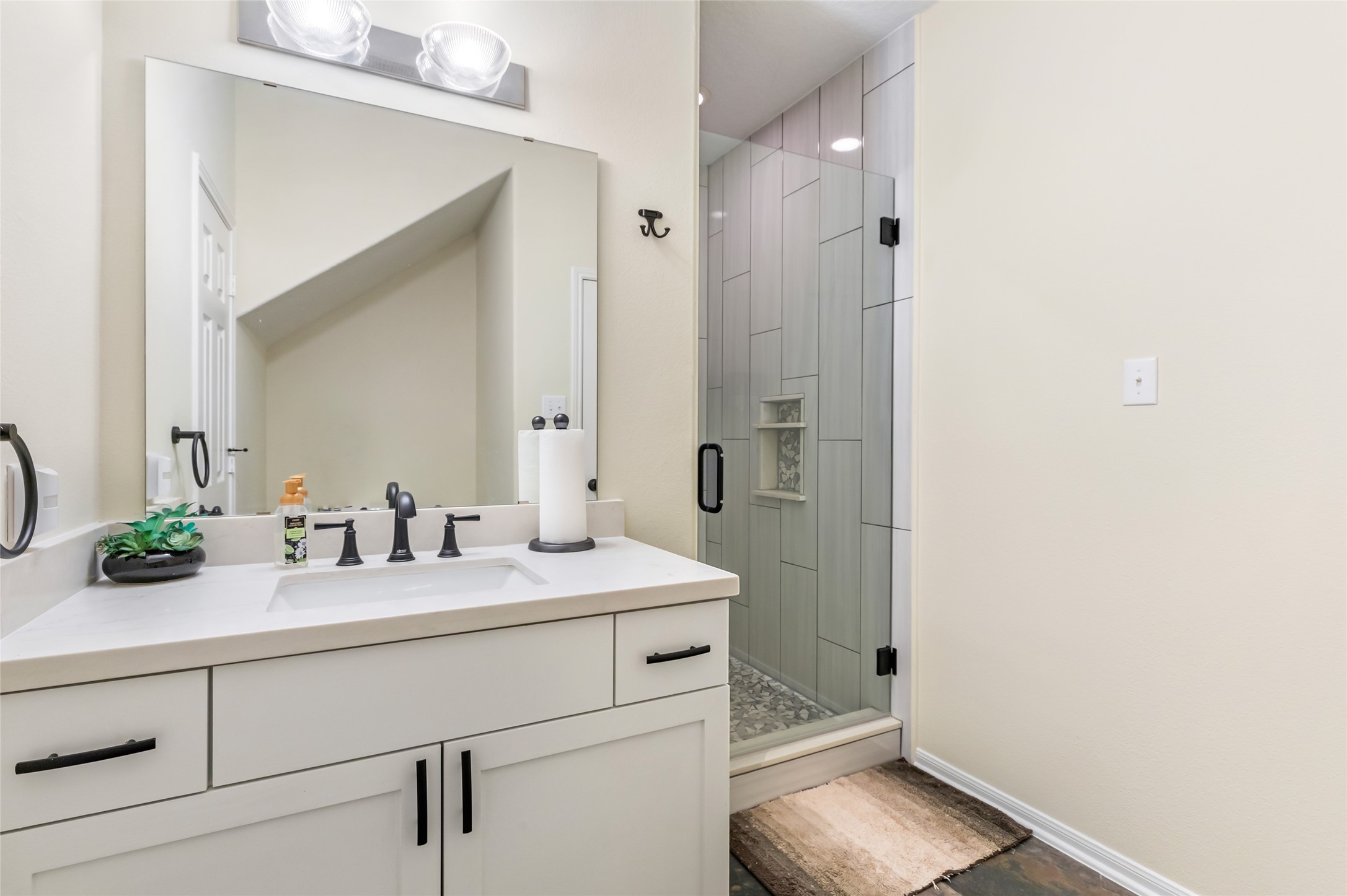 12122 Landsdown Ridge Way Humble, TX 77346 - Photo 22 of 34 This bathroom features a modern design with a spacious glass-enclosed shower, sleek white quartz countertop with black fixtures, and ample lighting.