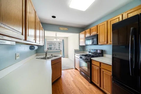 a kitchen with stainless steel appliances granite countertop a stove top oven a refrigerator a sink and dishwasher with wooden floor