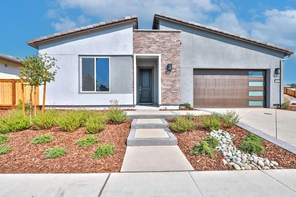a front view of a house with a yard and potted plants