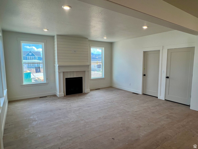 11507 Markfield Way, Unit 1124 South Jordan, UT 84009 - Photo 3 of 6 Living area featuring a central fireplace with a shiplap accent wall, white mantel, and hearth