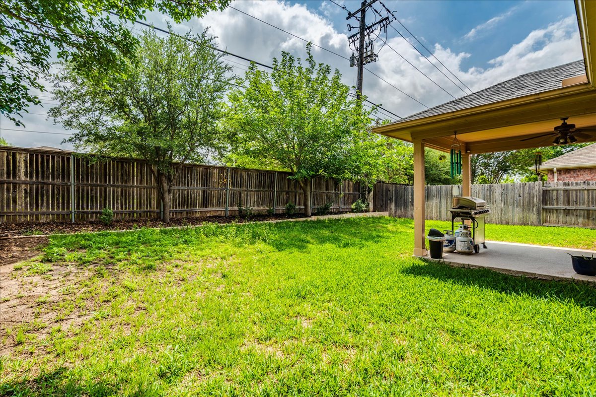 1151 Stone Rim Loop Buda, TX 78610 - Photo 27 of 36 The property features a spacious backyard with a well-maintained lawn and a covered patio area
