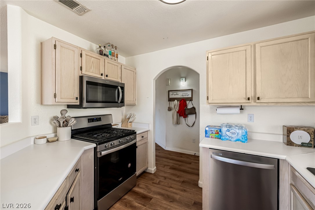698 South Racetrack Road, Unit 124 Henderson, NV 89015 - Photo 13 of 29 Kitchen with stainless steel appliances, light countertops, arched walkways, dark wood finished floors, and light wood finish cabinetry