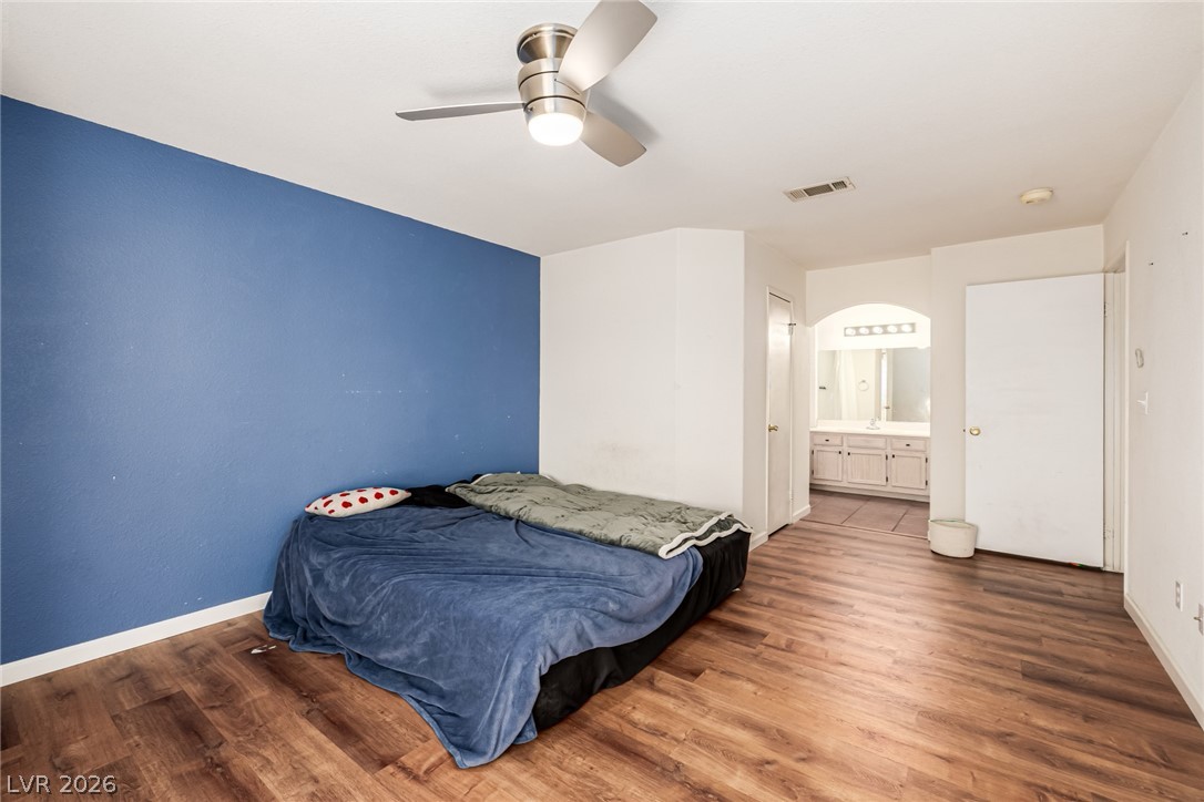 698 South Racetrack Road, Unit 124 Henderson, NV 89015 - Photo 14 of 29 Bedroom with dark wood-style floors, ceiling fan, ensuite bathroom, and arched walkways