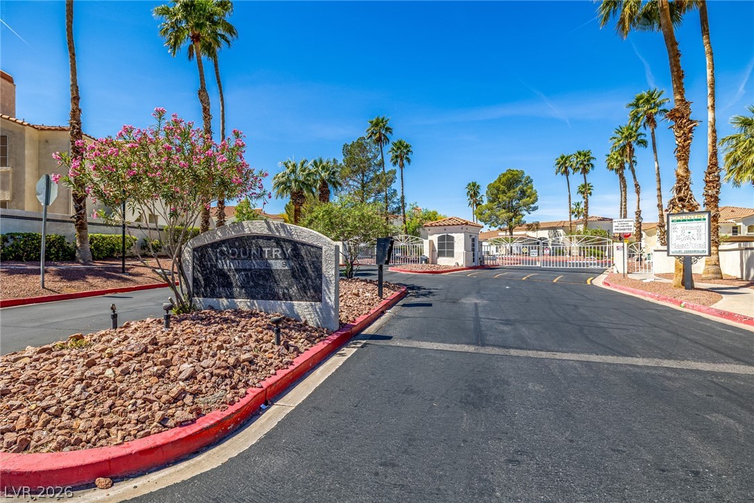 698 South Racetrack Road, Unit 124 Henderson, NV 89015 - Photo 26 of 29 View of asphalt road with a gate, curbs, traffic signs, a gated entry, and a residential view