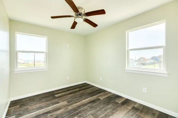 a view of empty room with wooden floor and window