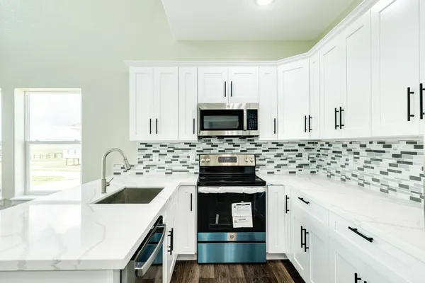 a kitchen with granite countertop a sink a stove and microwave