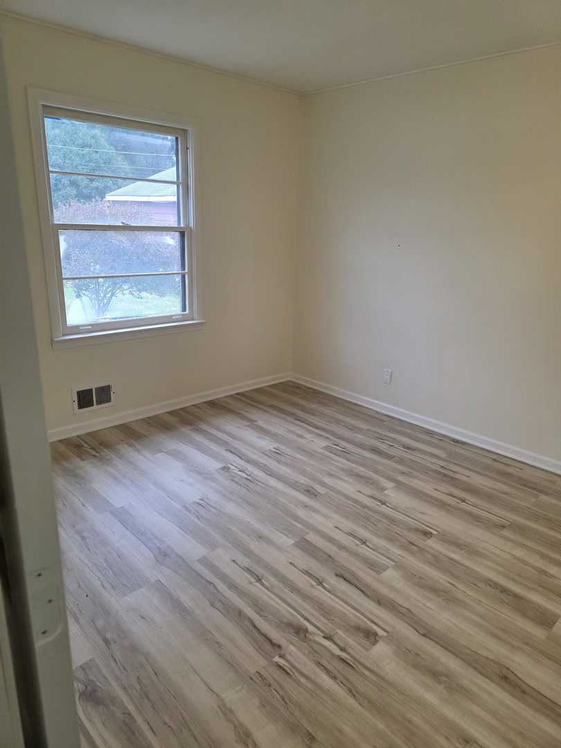 4905 143rd Place Midlothian, IL 60445 - Photo 7 of 17 a view of an empty room with wooden floor and a window