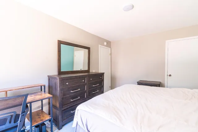 a bedroom with a bed and a mirror on dresser