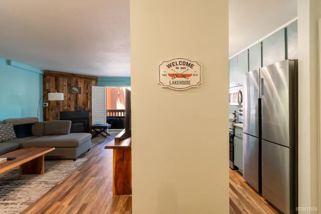a living room with stainless steel appliances furniture a refrigerator and a window