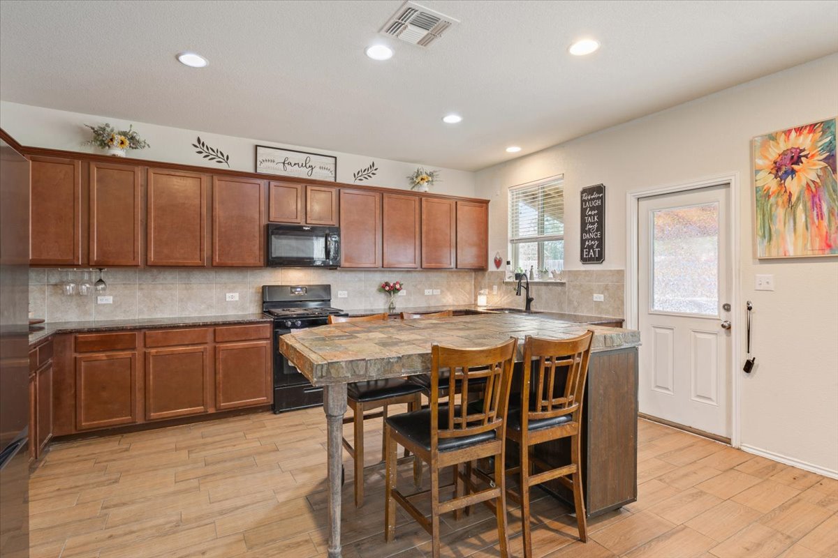 1500 Cliffbrake Way Georgetown, TX 78626 - Photo 11 of 35 Kitchen with light wood-style flooring, a kitchen island, and natural looking wood finish cabinetry