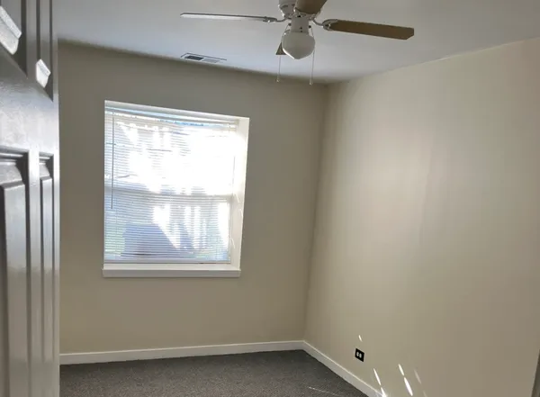 an empty room with a window and a fan
