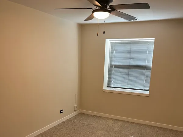 an empty room with a window and fan