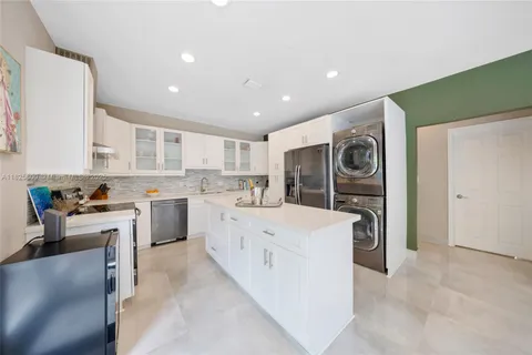 a large white kitchen with a stove a sink dishwasher and a refrigerator with wooden floor