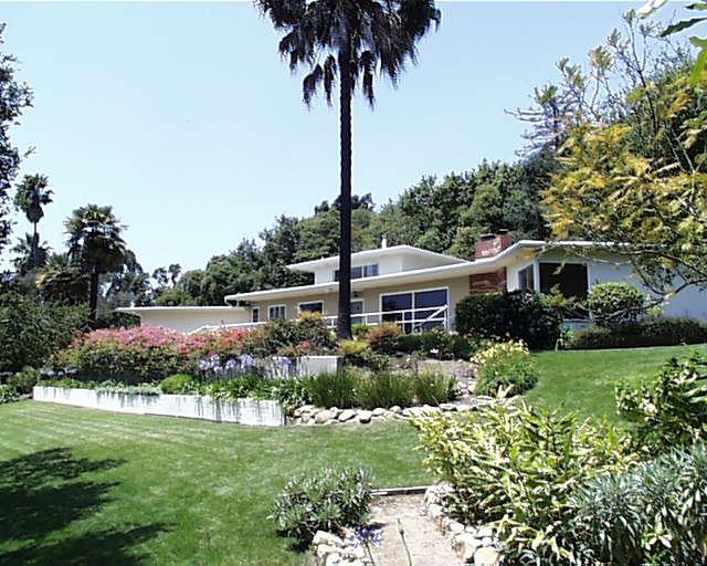 a front view of a house with a garden and trees