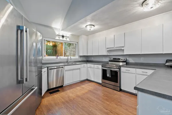 a view with granite countertop a sink white cabinets and a wooden floor