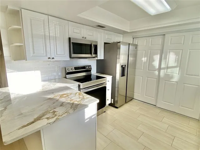 a kitchen with granite countertop a refrigerator and a sink