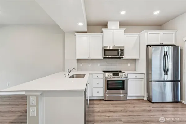 a kitchen with stainless steel appliances a sink cabinets and wooden floor