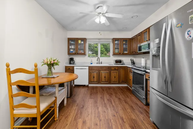 a kitchen with stainless steel appliances granite countertop a refrigerator a sink dishwasher a stove and white countertops with wooden floor