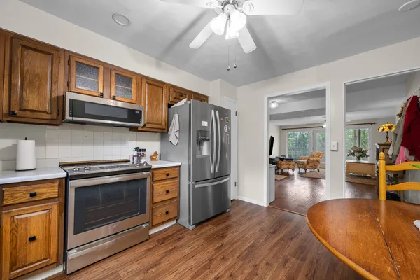 a kitchen with stainless steel appliances granite countertop a refrigerator a stove oven a sink dishwasher a dining table and chairs with wooden floor