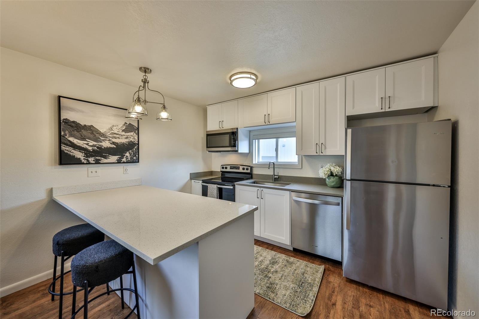 233 Fraser Avenue, Unit R1 Fraser, CO 80442 - Photo 2 of 23 a kitchen with stainless steel appliances a refrigerator a stove a sink dishwasher and white cabinets with wooden floor