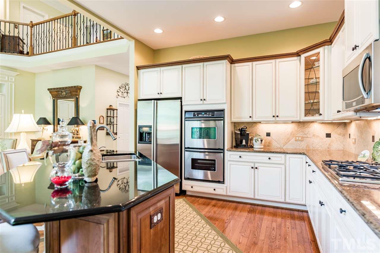 2247 Clayette Court Raleigh, NC 27612 - Photo 12 of 25 a kitchen with stainless steel appliances kitchen island granite countertop a refrigerator oven a sink dishwasher and white cabinets with wooden floor