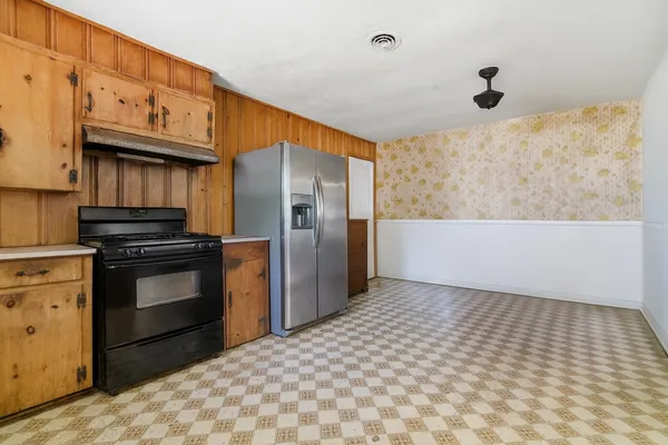 a kitchen with granite countertop a stove a refrigerator and cabinets