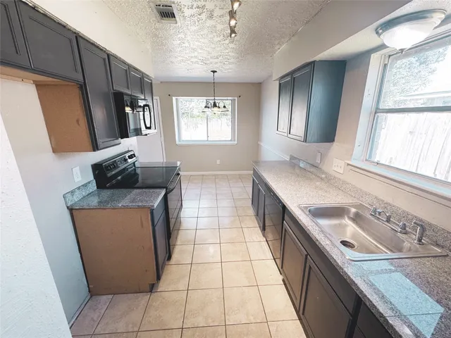 a kitchen with granite countertop a sink stove and cabinets