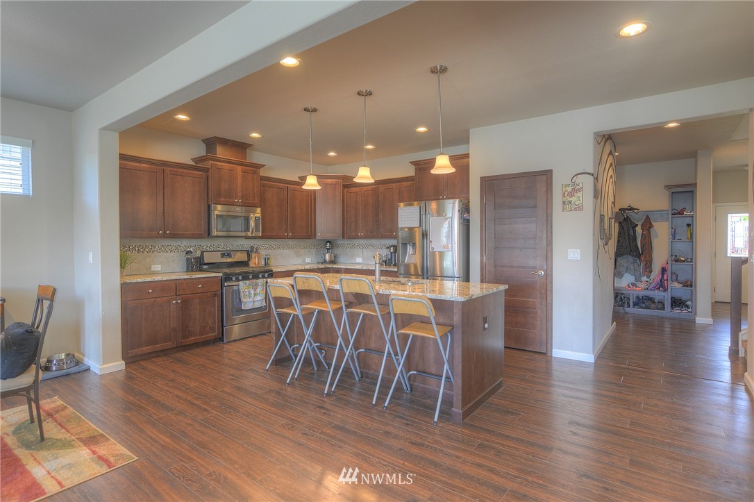 4745 Rosa Court Lacey, WA 98503 - Photo 8 of 25 a kitchen with a dining table chairs wooden floor cabinets and stainless steel appliances